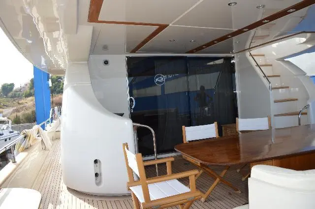 Riva Opera 85 — Cockpit arrière avec table en bois, fauteuils et banquette d’un bateau.