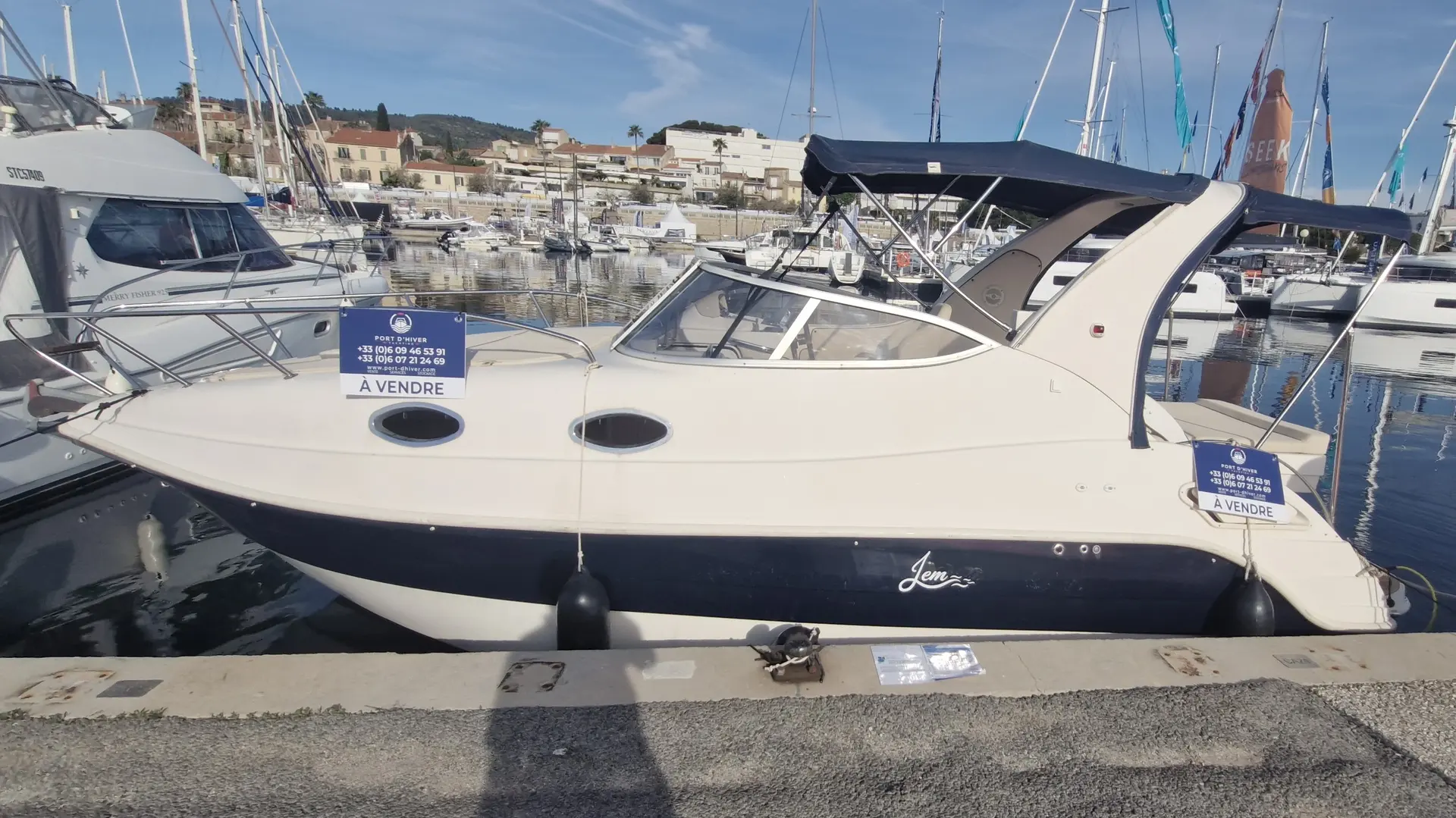 Eolo 770 Cruiser — Bateau à moteur blanc et bleu amarré dans une marina, vu de profil.