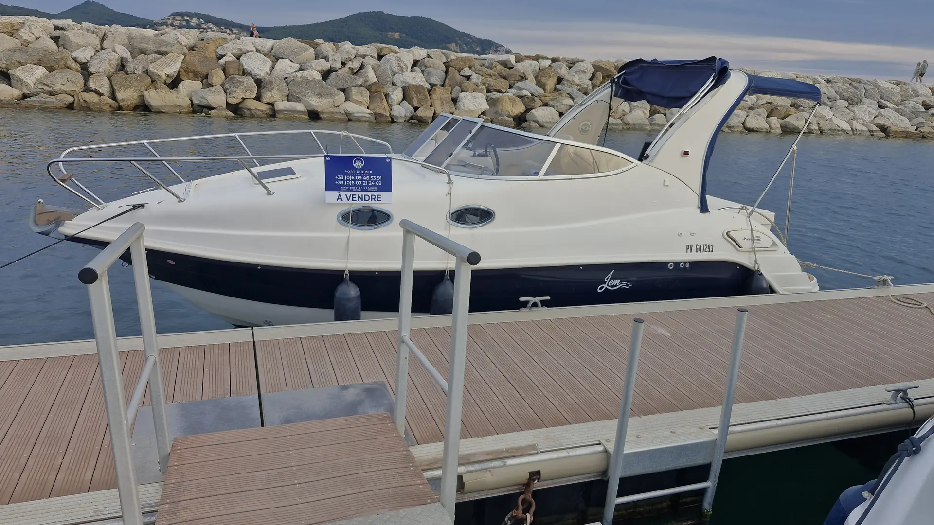 Eolo 770 Cruiser — Bateau à moteur blanc amarré le long d’une digue, vu de profil.