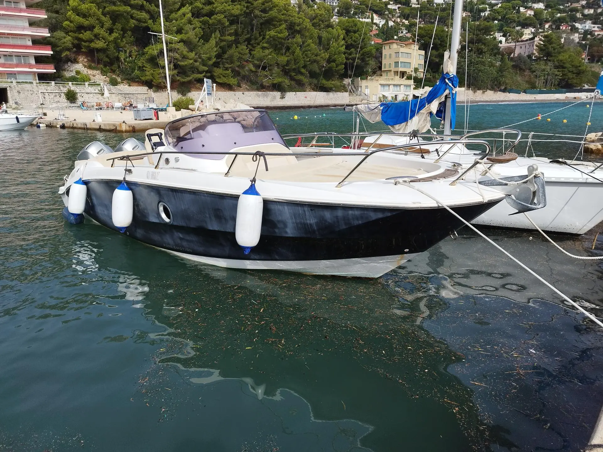 Sessa Marine Key Largo 27 — Bateau à moteur blanc et noir amarré dans un port, vu de trois quarts avant.