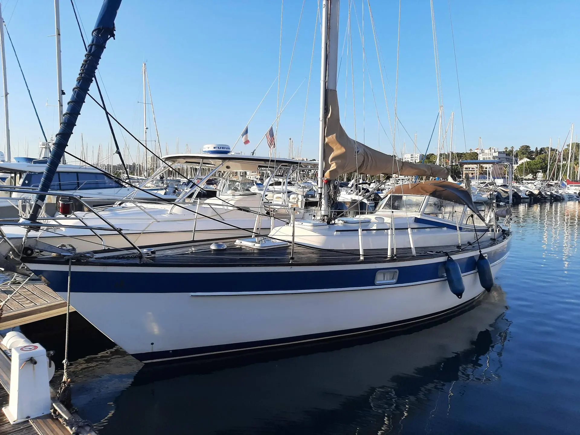 Hallberg Rassy 312 — Voilier amarré dans une marina, photographié de trois quarts par bâbord.