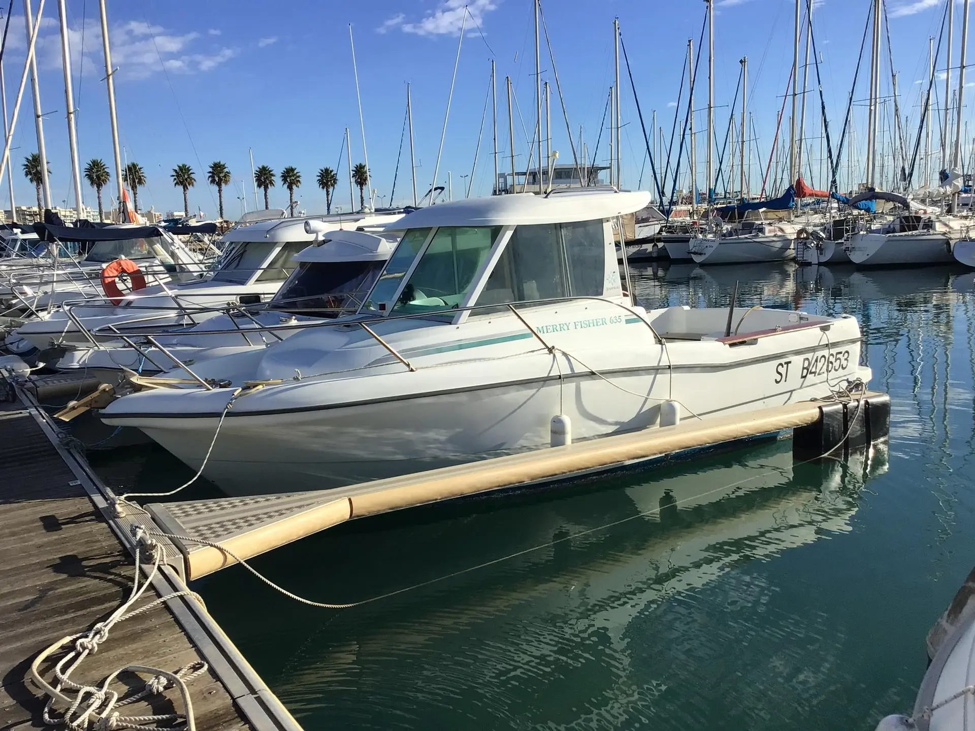 Jeanneau Merry Fisher 635 — Bateau à moteur blanc amarré dans un port de plaisance.