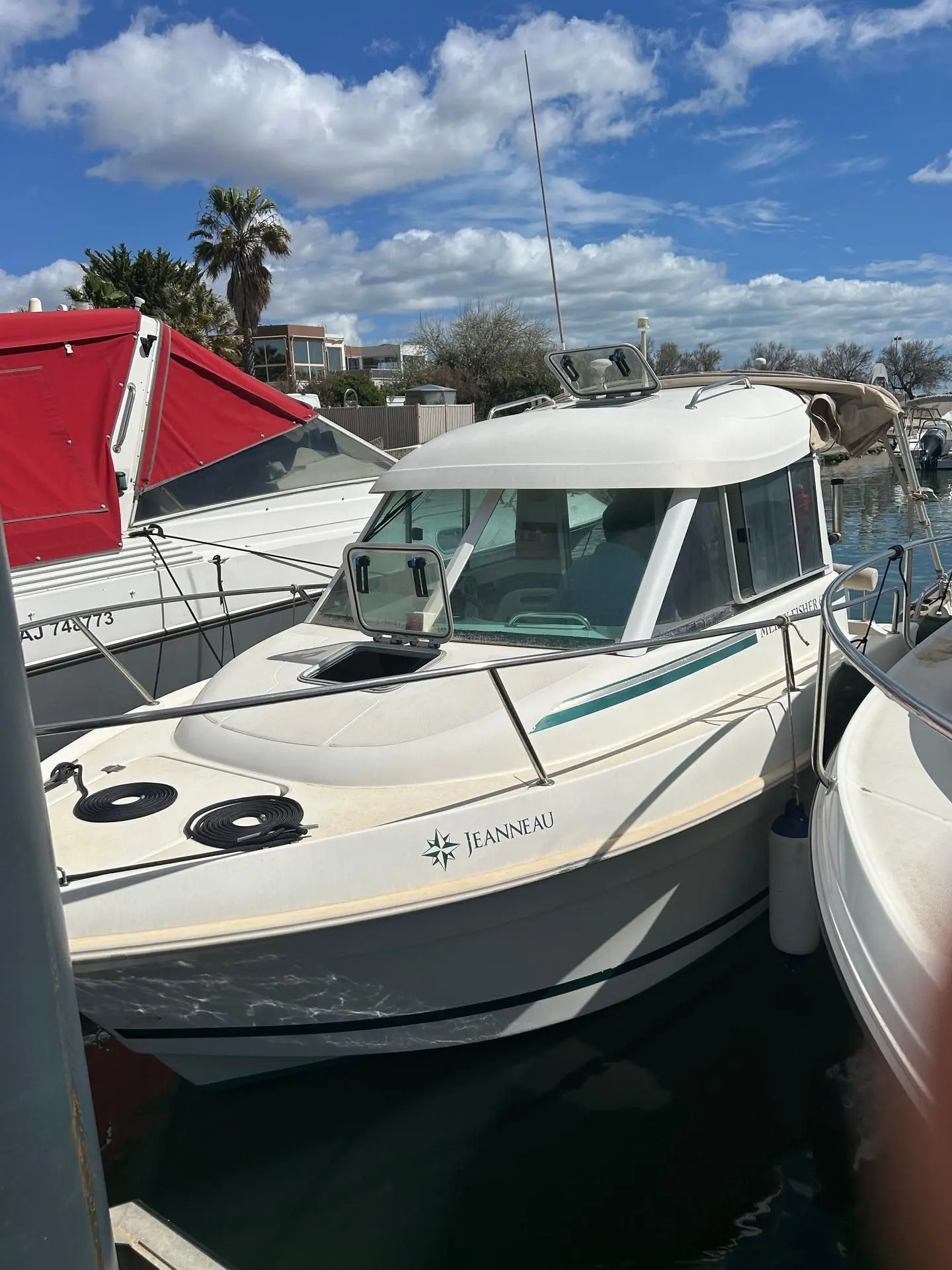 Jeanneau Merry Fisher 625 — Bateau à moteur blanc amarré dans un port, vu de trois quarts avant.
