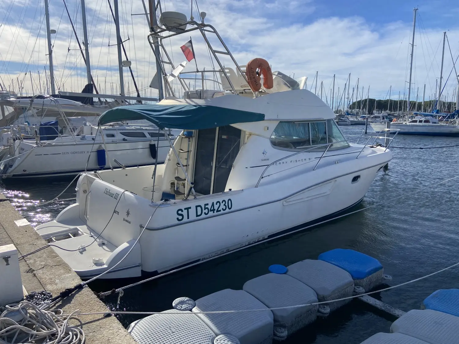Jeanneau Merry Fisher 925 — Bateau à moteur blanc amarré dans une marina, vu de trois quarts arrière.