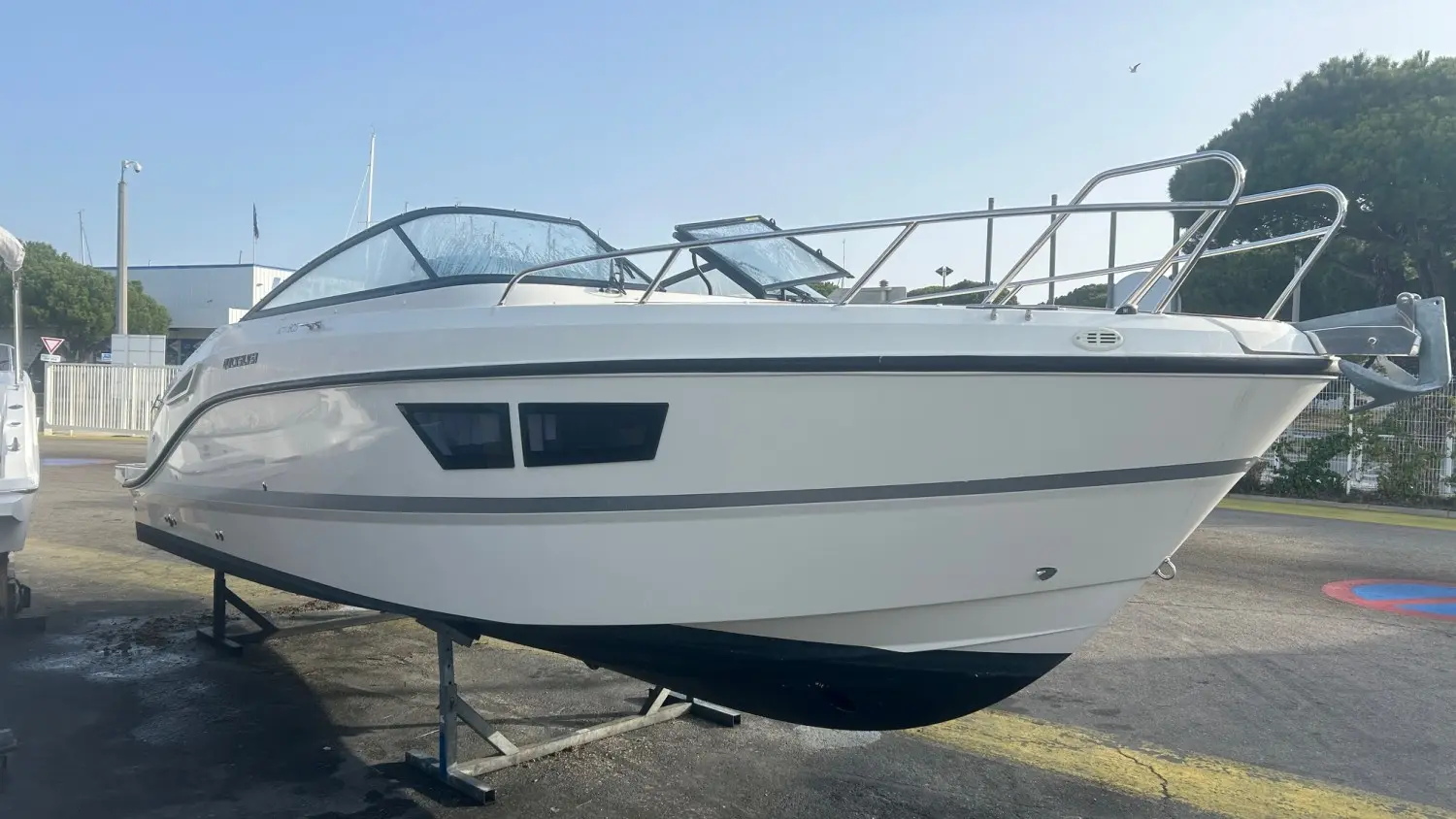 Quicksilver 805 Cruiser — Bateau blanc à cabine, vu de trois quarts sur remorque dans une cour extérieure.