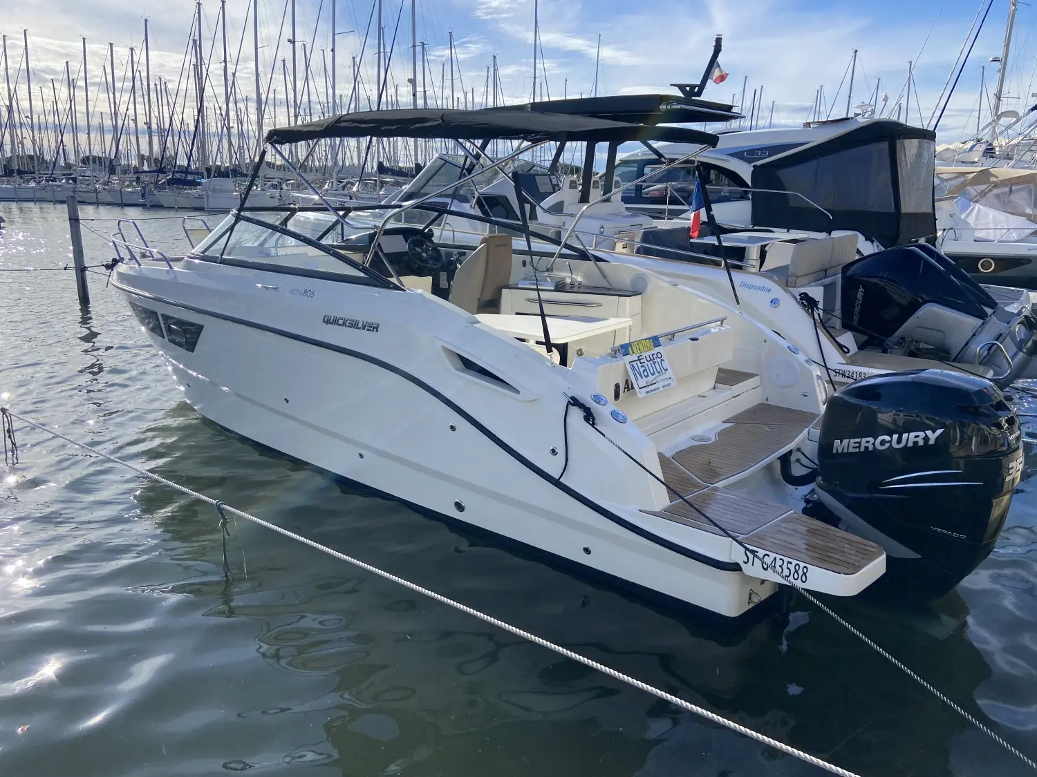 Quicksilver 805 Cruiser — Bateau à moteur blanc amarré dans un port, vu de trois quarts arrière.