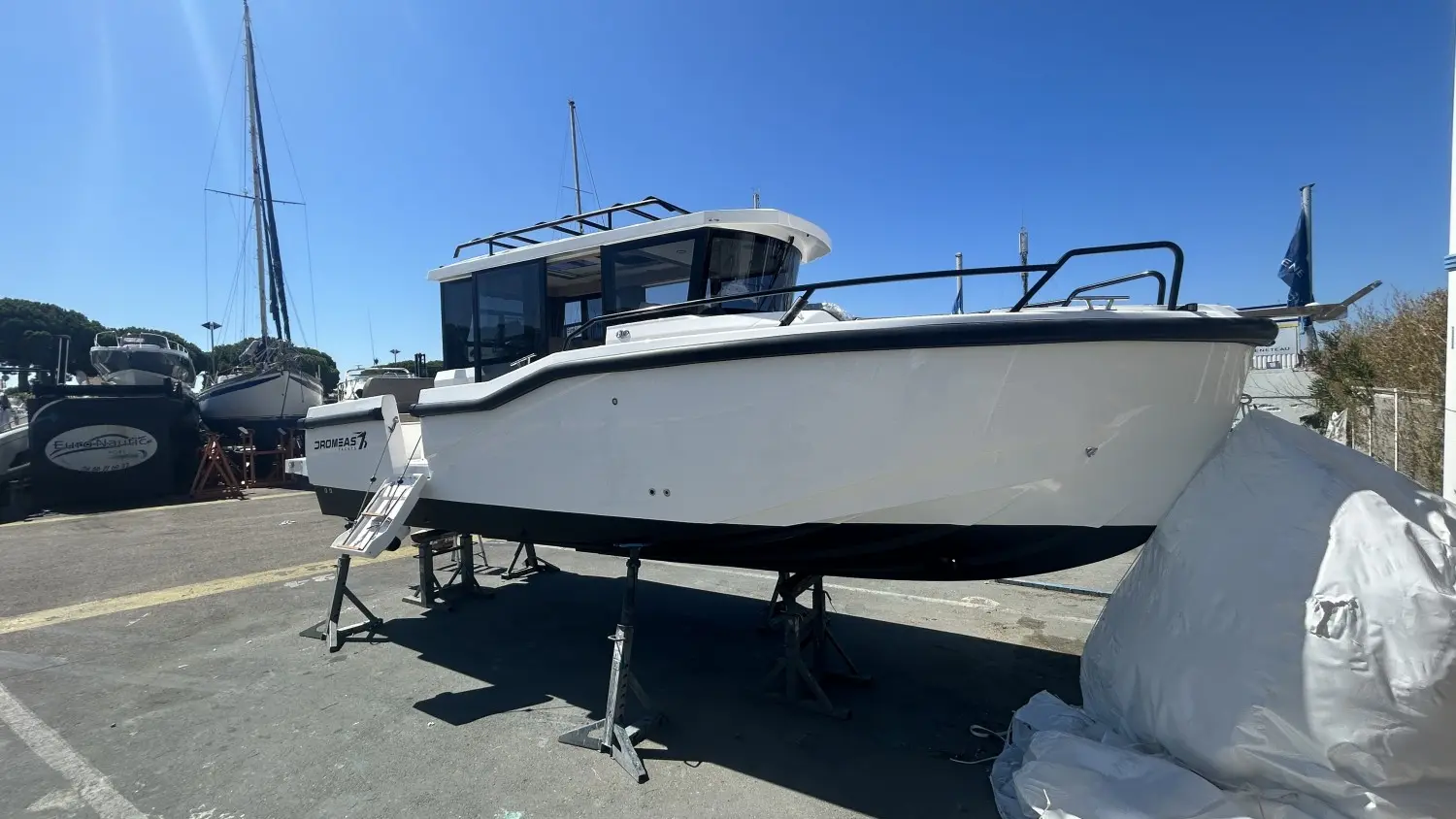 Dromeas Yachts D28 SUV — Bateau à moteur blanc présenté à terre sur bers dans un port.
