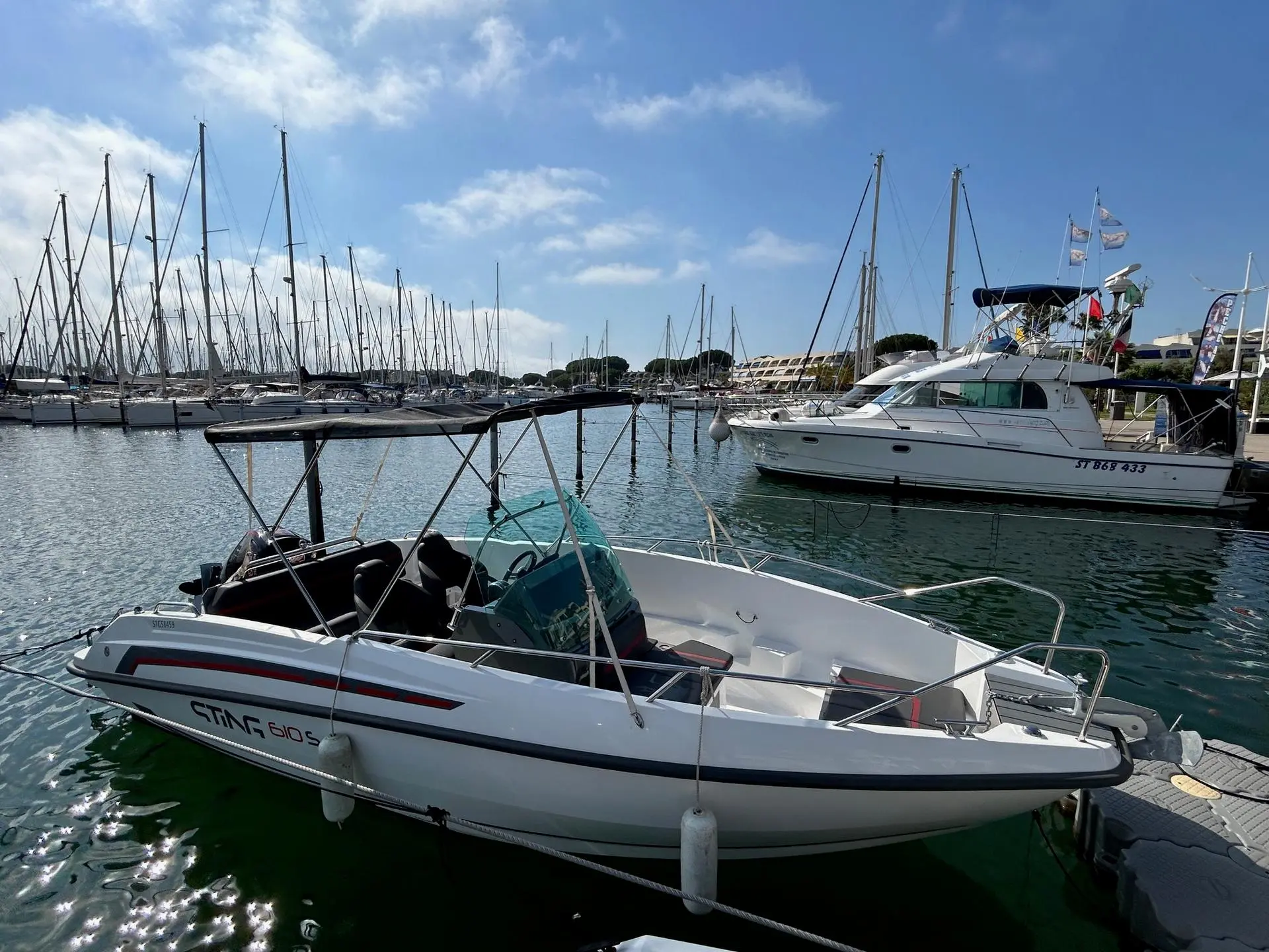 Sting 610 S — Bateau à moteur blanc vu de trois quarts, amarré dans une marina ensoleillée.