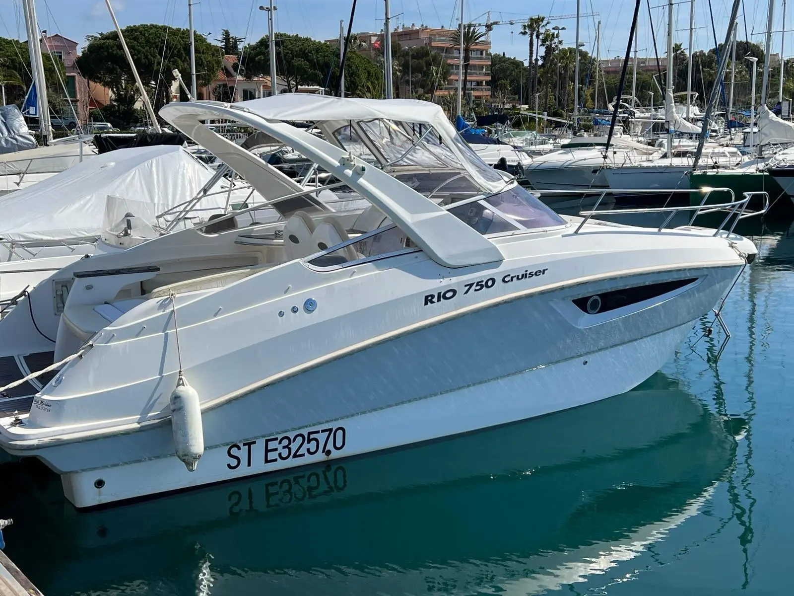 Rio 750 — Veduta laterale d’un cabiné blanc amarré dans un port de plaisance.
