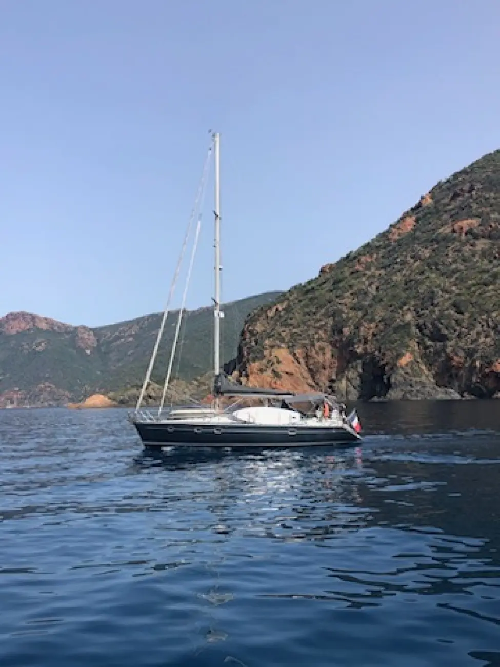 Kirie Feeling 416 — Voilier vu de profil au mouillage dans une crique rocheuse.