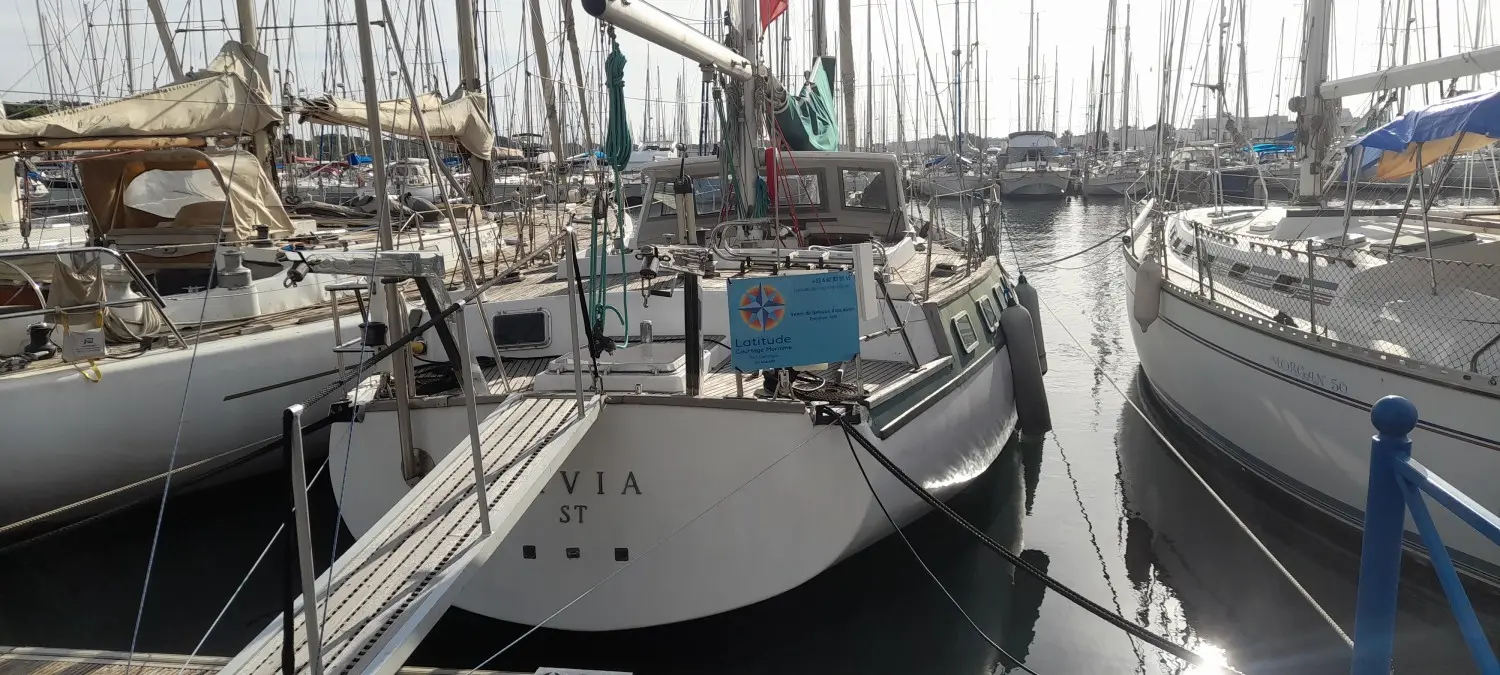 CNSO Mikado — Voilier amarré dans un port, photographié de poupe entre deux autres bateaux.