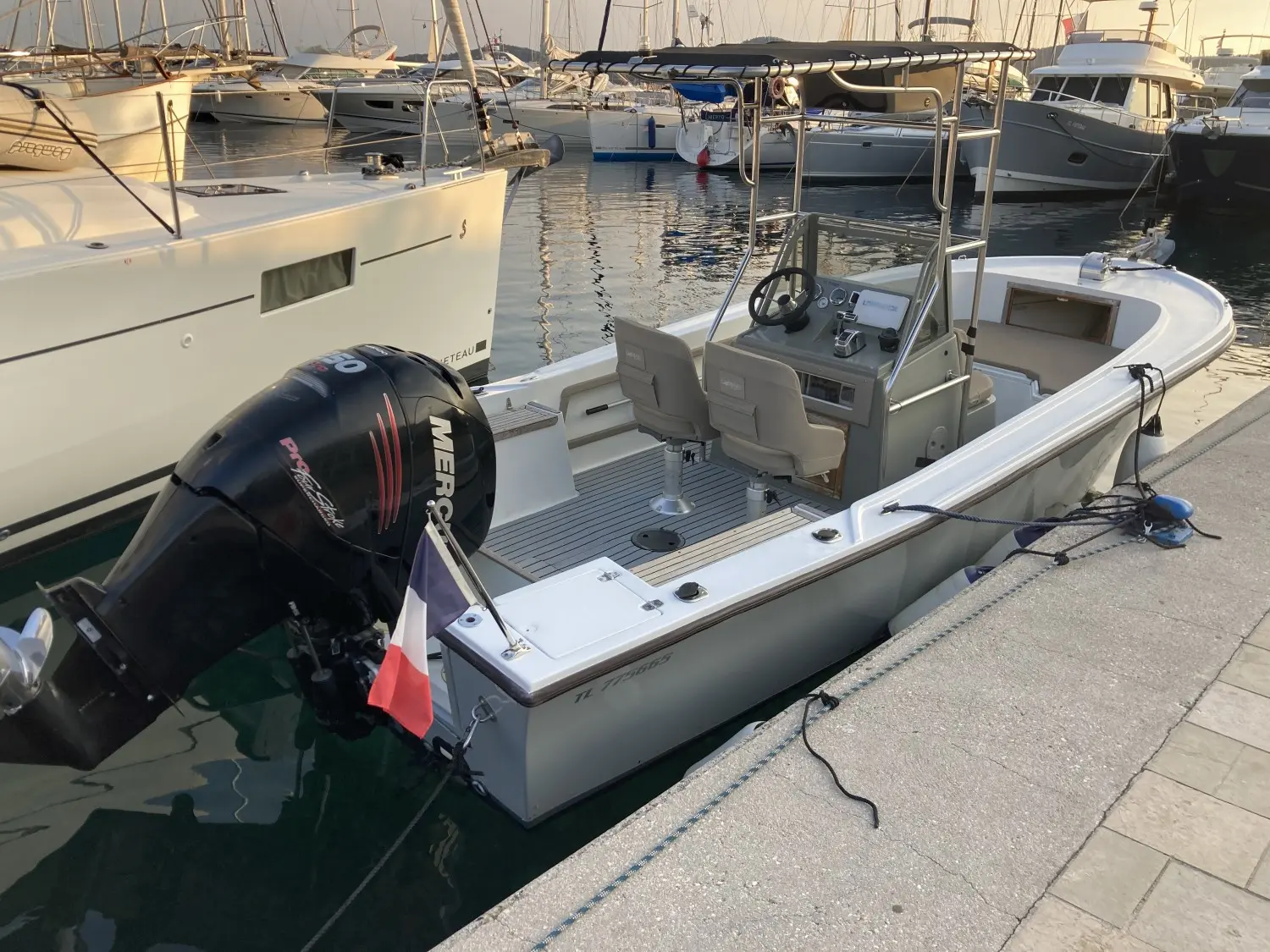 Mako 211 — Bateau à moteur hors-bord amarré dans un port, vu de trois quarts arrière.