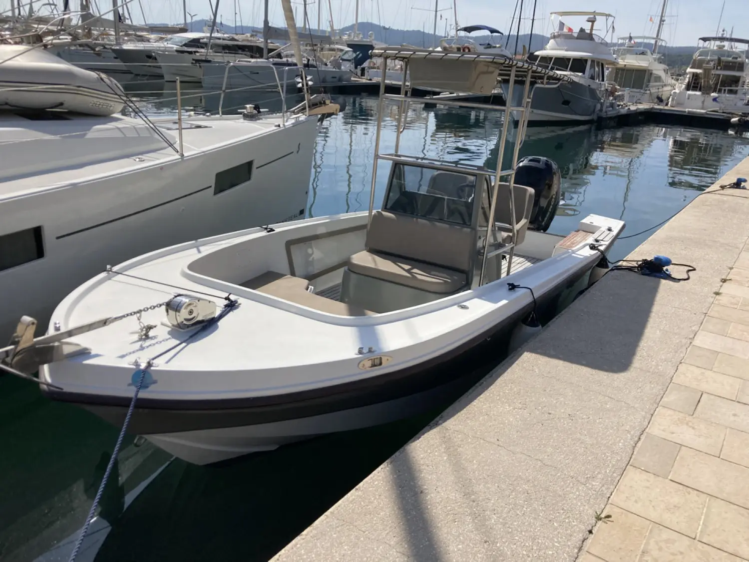 Mako 211 — Bateau à moteur blanc amarré dans une marina, vu de trois quarts avant.