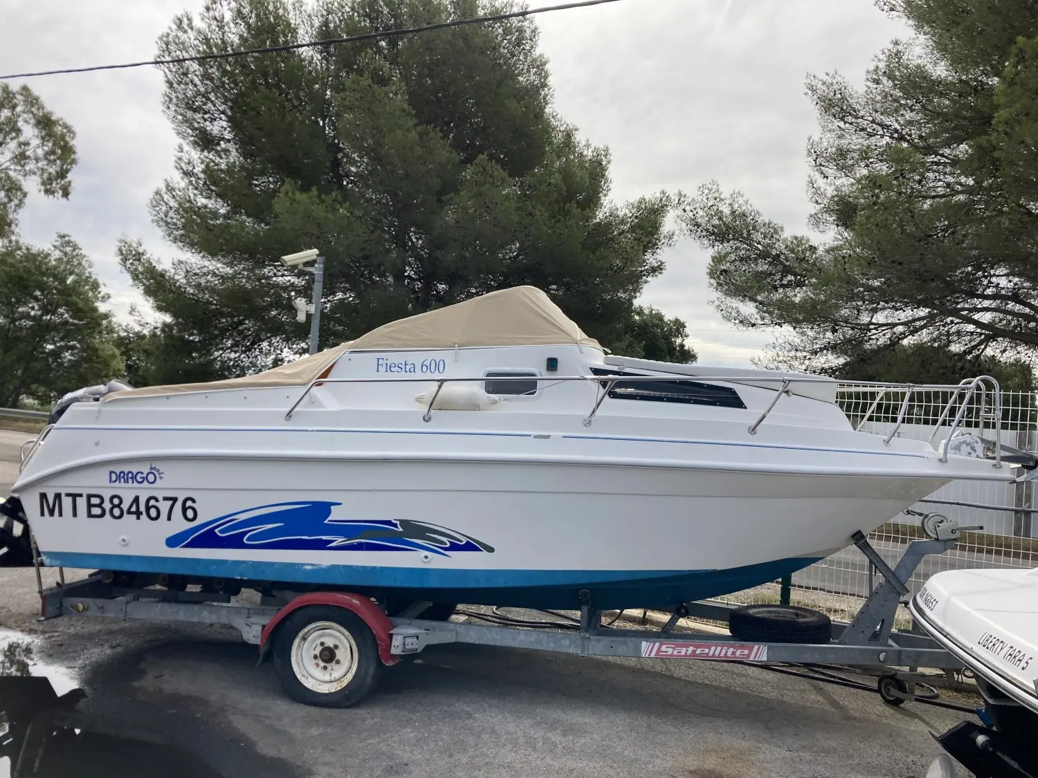Drago Fiesta 600 — Bateau à moteur blanc bâché, photographié sur sa remorque à terre.