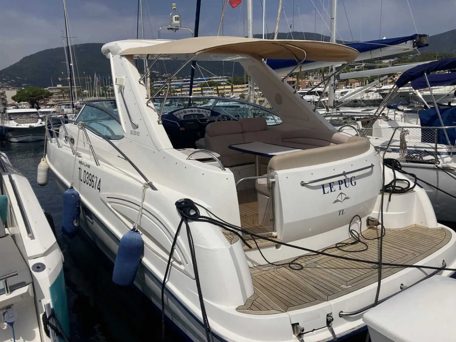 Sealine S 38 — Bateau à moteur blanc vu de trois quarts arrière dans un port de plaisance.
