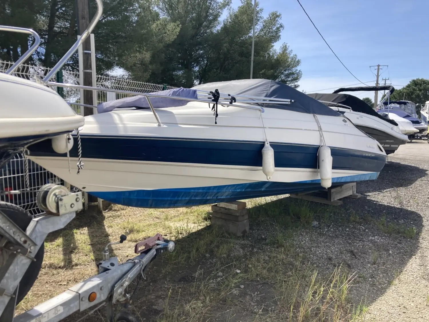 Bayliner Capri Cuddy 2052 — Bateau à moteur blanc et bleu présenté sur bers dans un parc nautique.