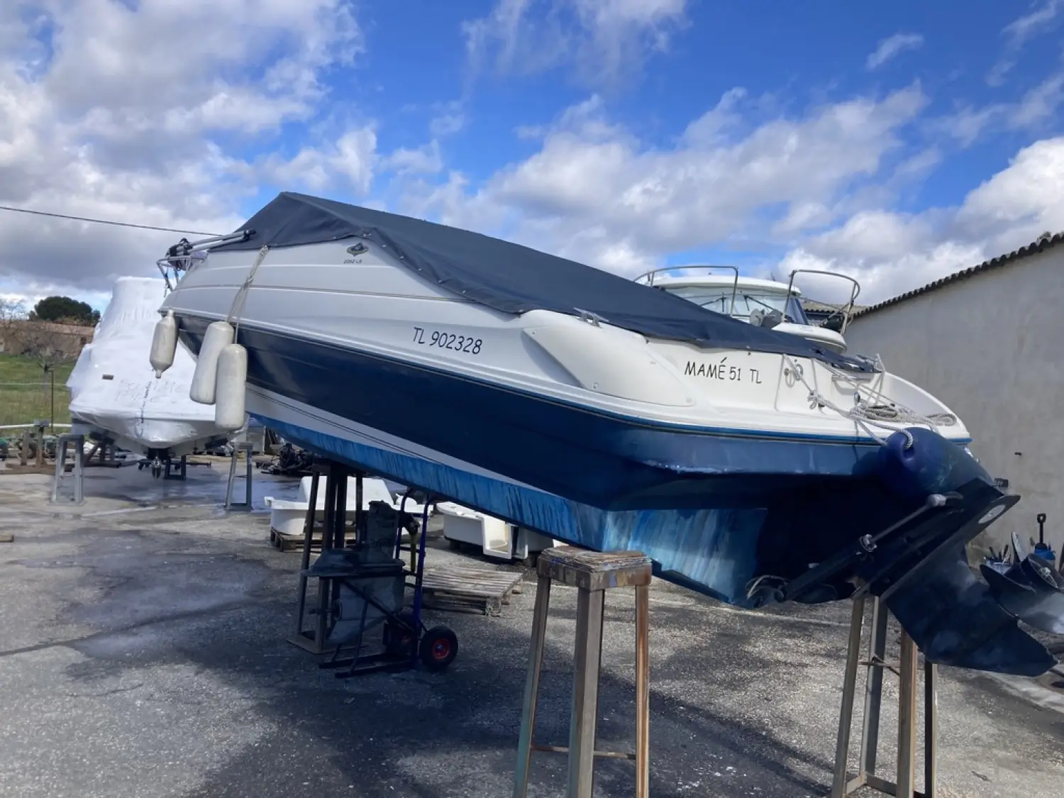 Bayliner Capri Cuddy 2052 — Bateau à moteur bleu et blanc photographié à terre, bâché sur supports.