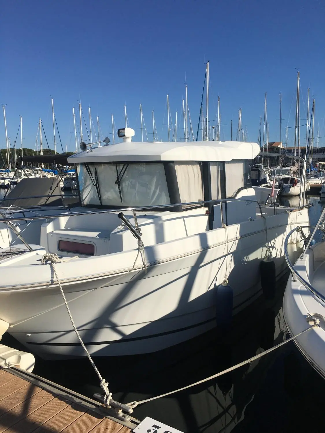 Jeanneau Merry Fisher 855 — Vedette à cabine blanche amarrée dans un port de plaisance.