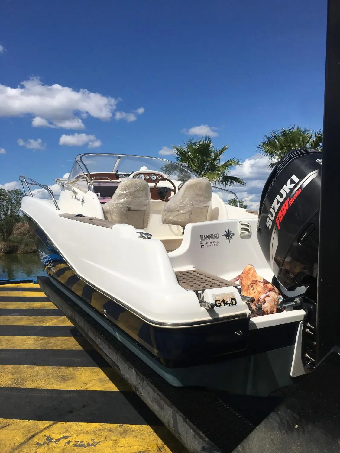 Jeanneau Cap Camarat 755 — Bateau vu depuis l’arrière, avec cockpit, sièges protégés et moteur hors-bord.