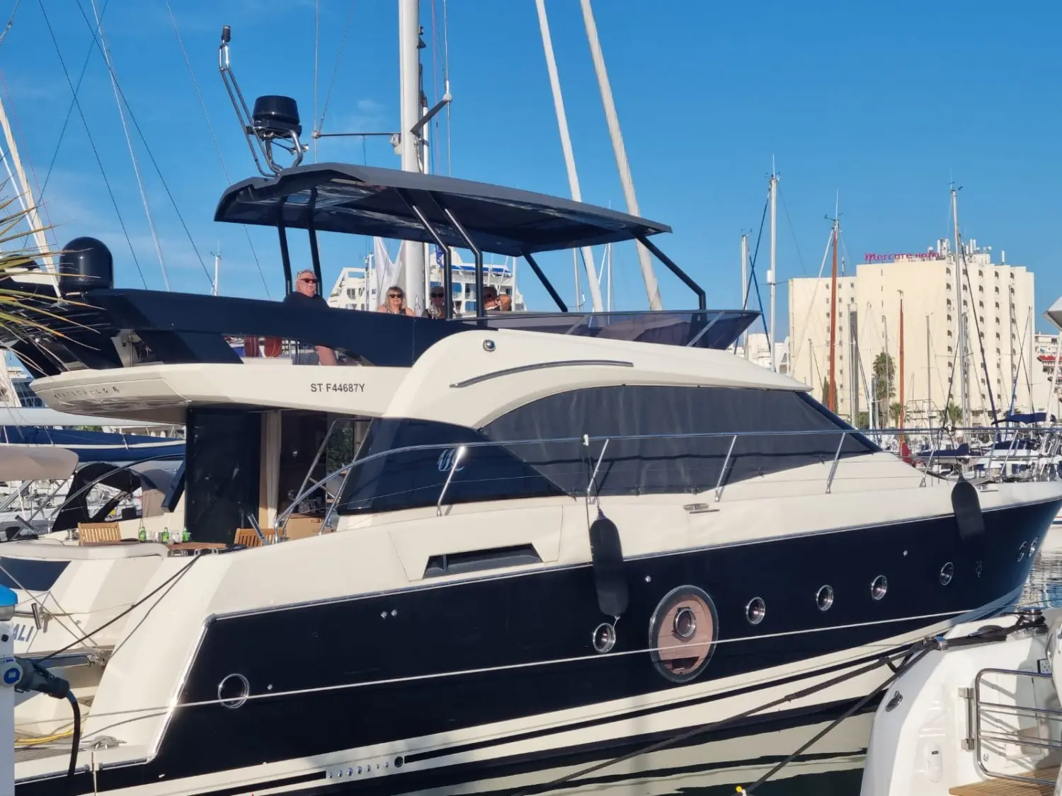 Beneteau Monte Carlo 6 — Vedette à moteur amarrée dans un port, vue latérale trois-quarts.