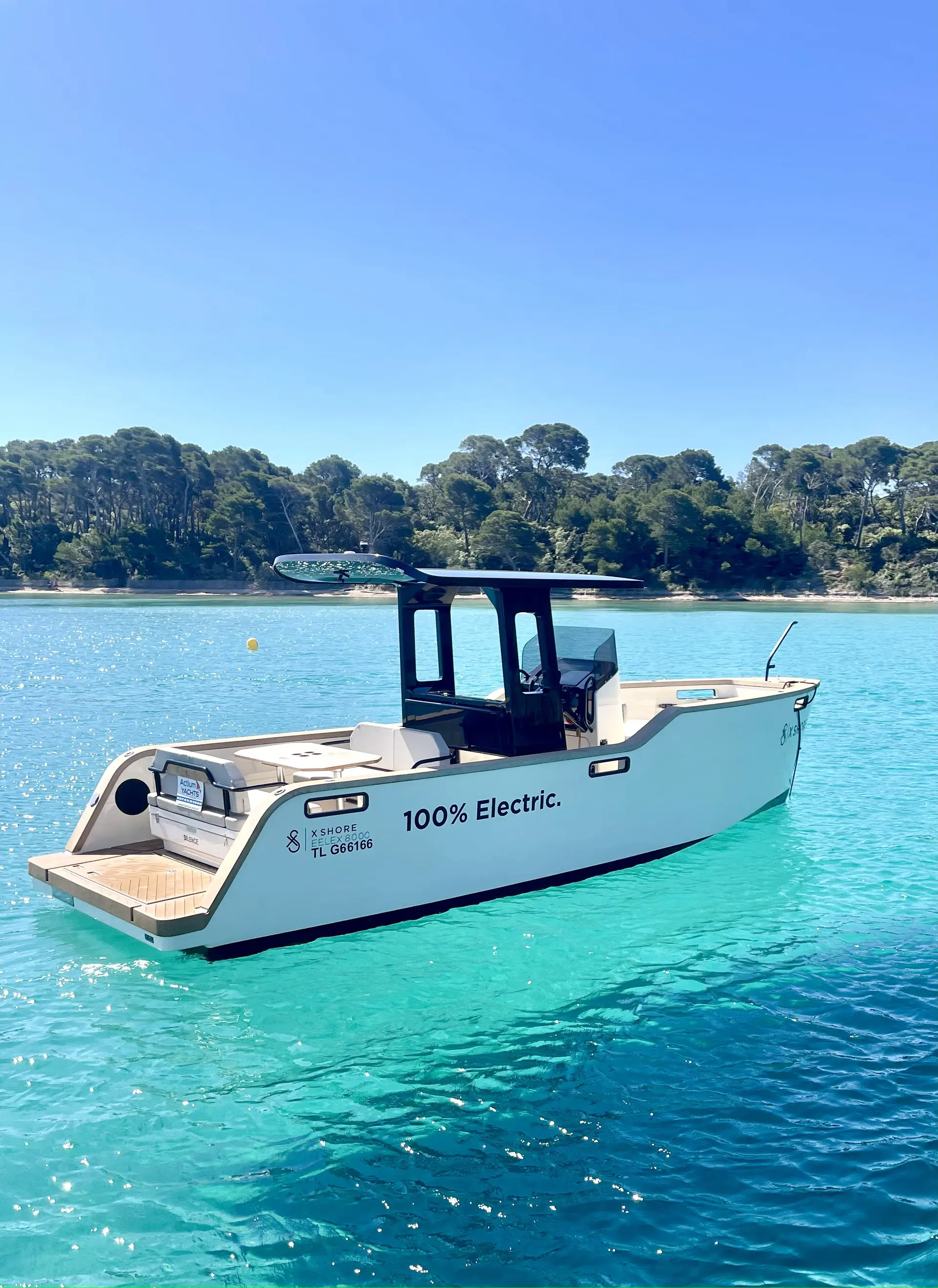 Xshore Eelex 8000 — Bateau électrique vu de trois quarts dans une baie turquoise.