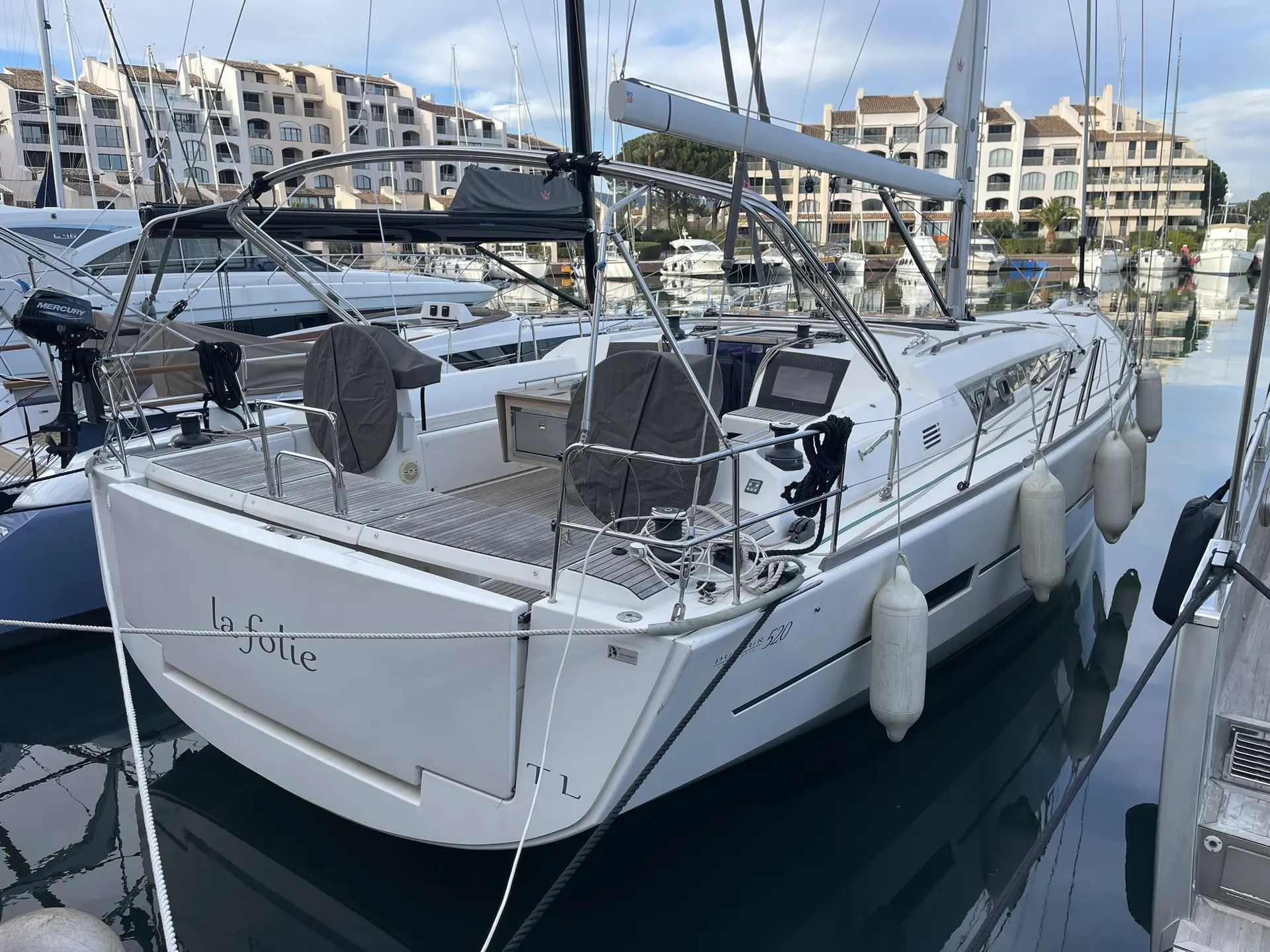 Dufour 520 Grand Large — Voilier blanc vu de trois quarts arrière, amarré dans une marina.