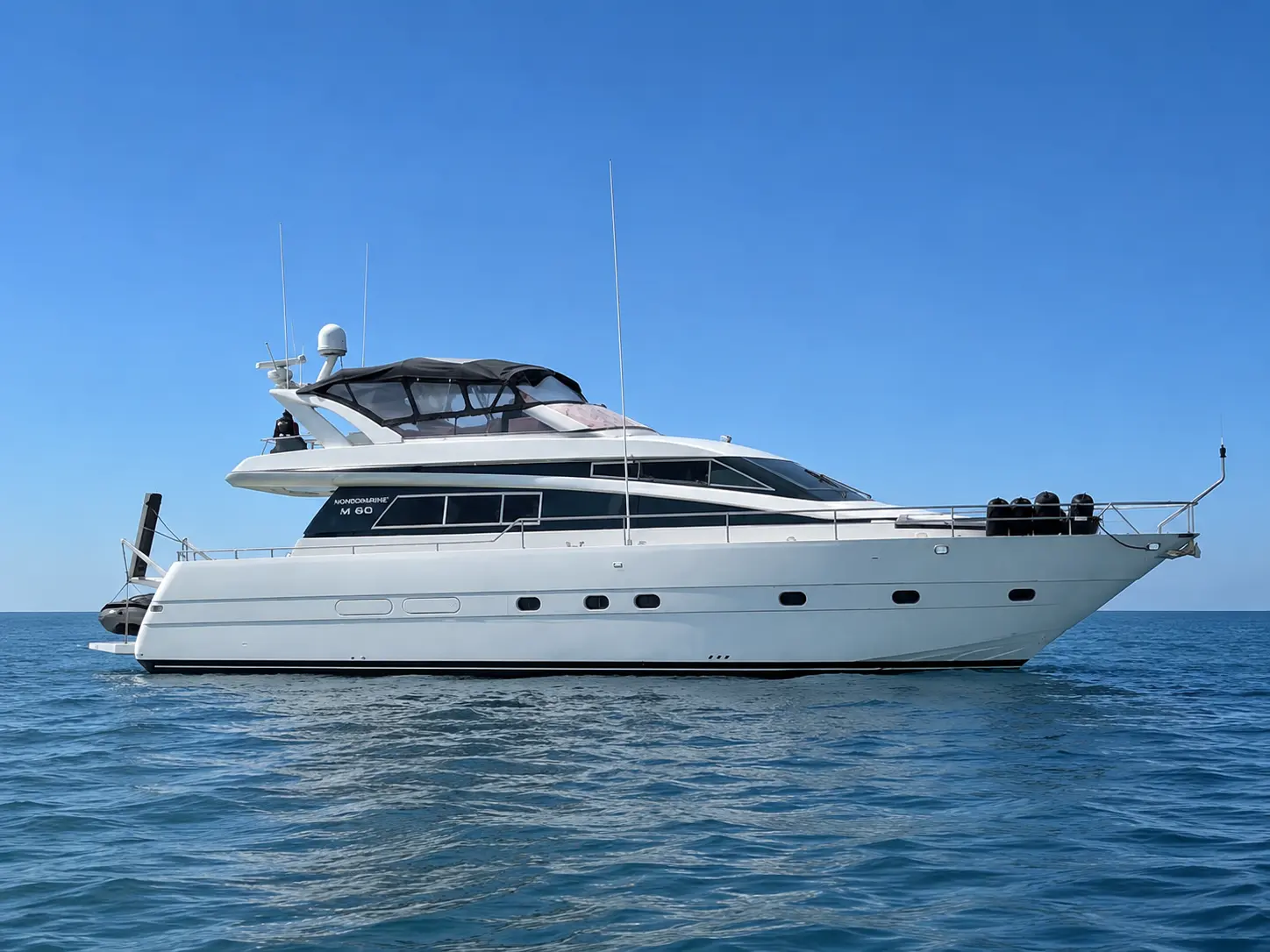 Mondomarine M 60 — Vue de profil d’un yacht à moteur blanc naviguant en mer sous un ciel dégagé.