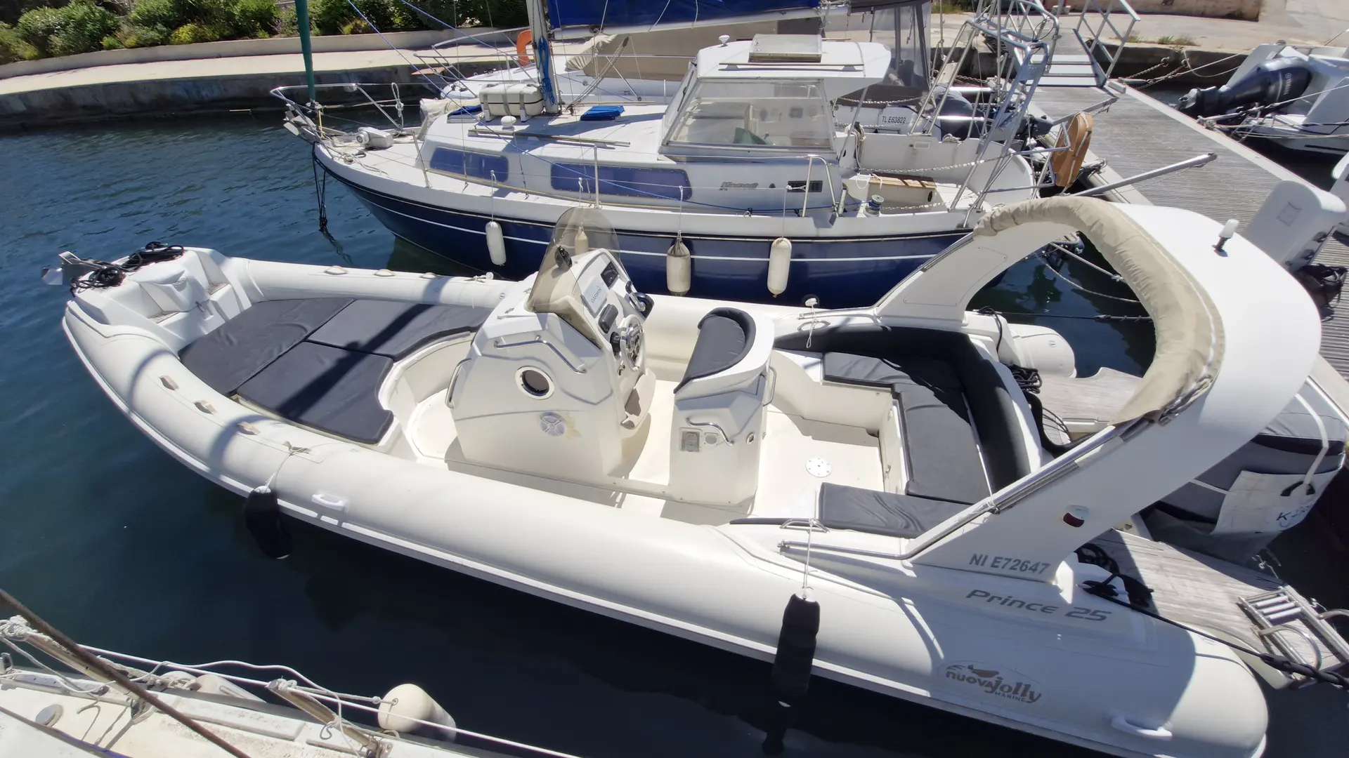 Nuova Jolly Prince 25 — Vue en plongée d’un semi-rigide blanc amarré dans un port.