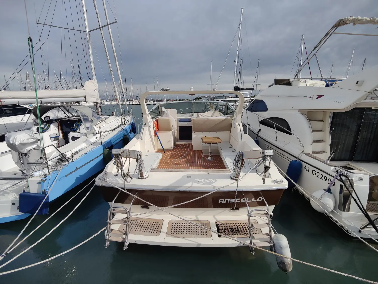 Raffaelli Typhoon Middle Day — Vue arrière d’un bateau à moteur amarré dans un port, entouré d’autres embarcations.