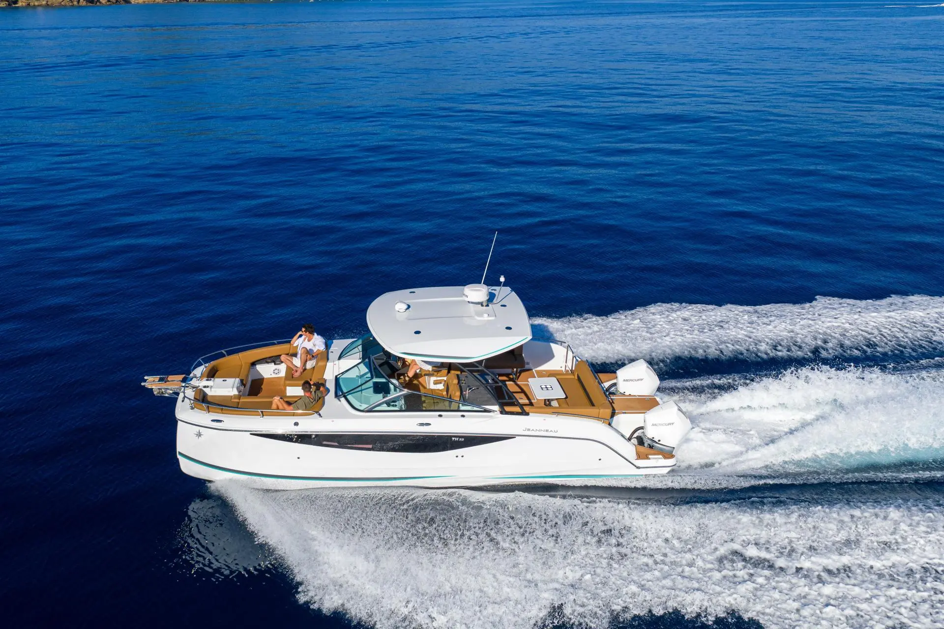 Jeanneau TH 33 — Bateau à moteur blanc vu de trois quarts, naviguant à vive allure en mer.