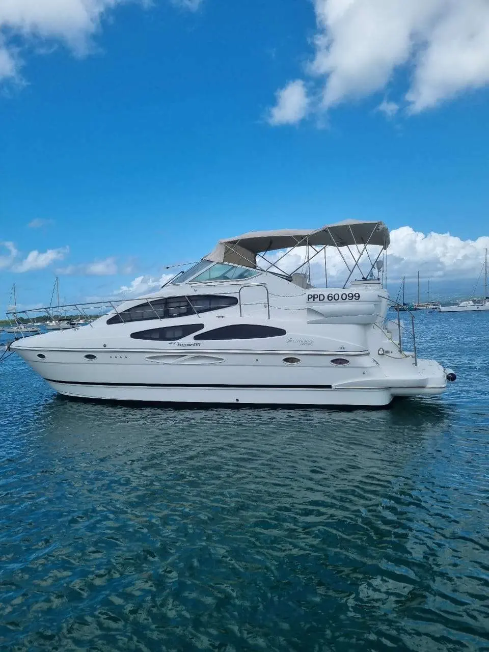 Cruisers Yachts 415 — Bateau à moteur blanc photographié de profil sur l’eau, sous un ciel nuageux.