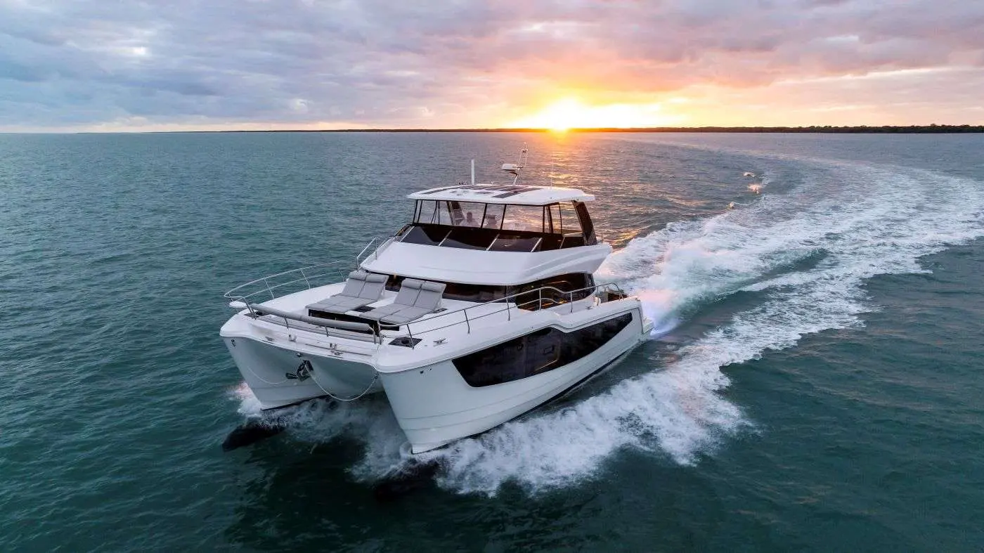 Aquila 50 — Catamaran à moteur blanc naviguant au coucher du soleil, vu de trois quarts avant.