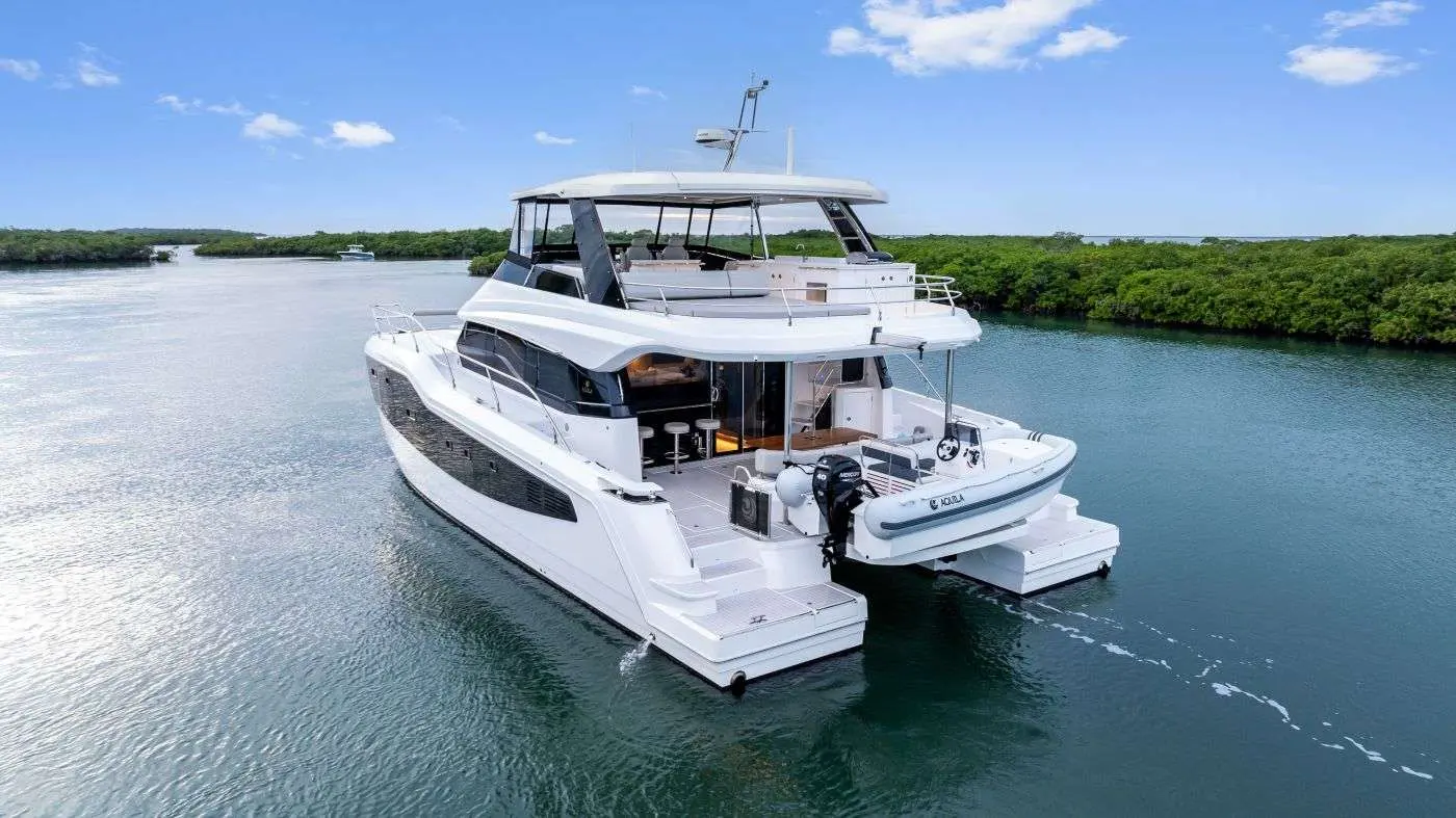Aquila 50 — Bateau à moteur blanc vu de trois quarts arrière sur un chenal bordé de mangroves.