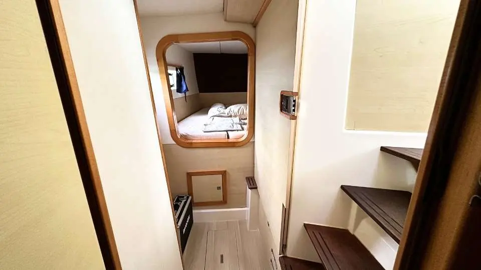Catana 42 — Vue d’un passage intérieur menant à une cabine avec couchette et rangements.