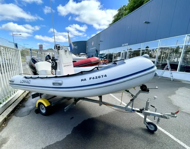 Lomac 400 Open — Bateau pneumatique blanc sur remorque devant un bâtiment.