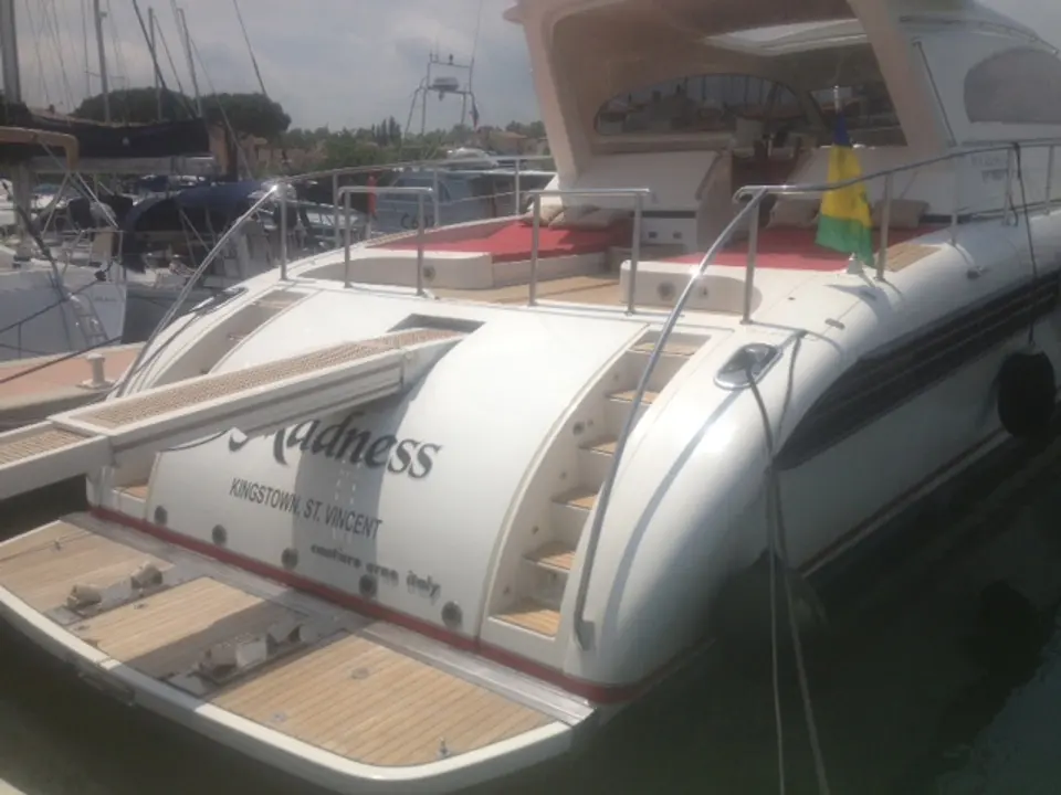 Arno Leopard 23 — Vue arrière d’un yacht blanc amarré, avec plage de bain et coussins rouges.