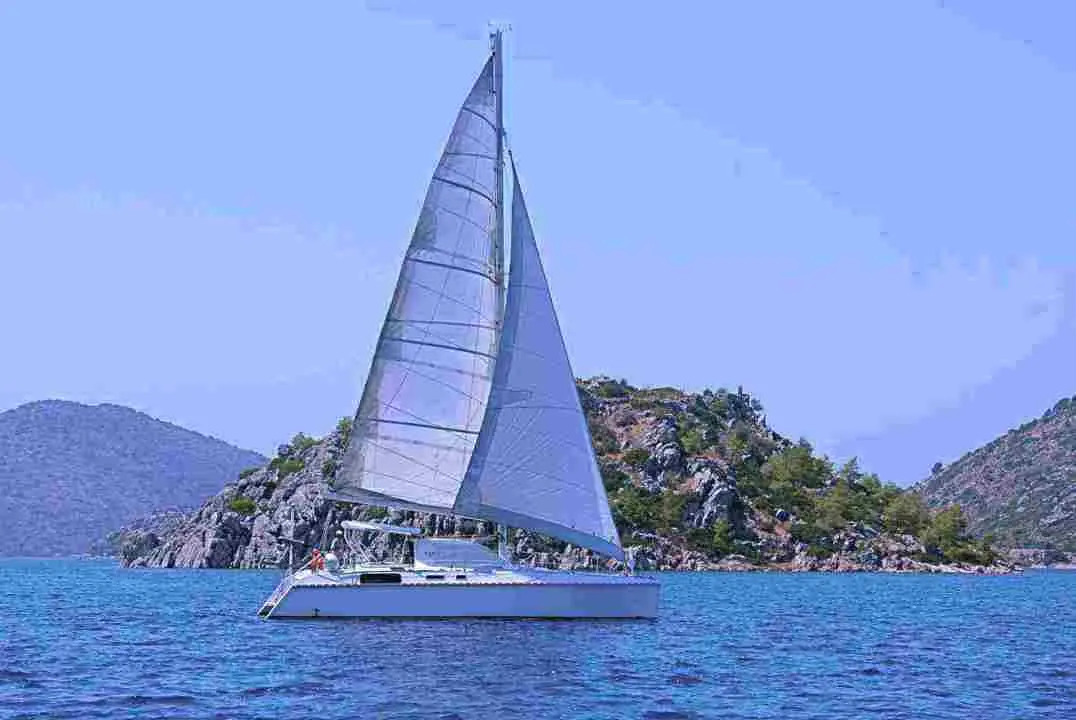 Catana 42 — Catamaran à voiles naviguant devant une côte rocheuse.