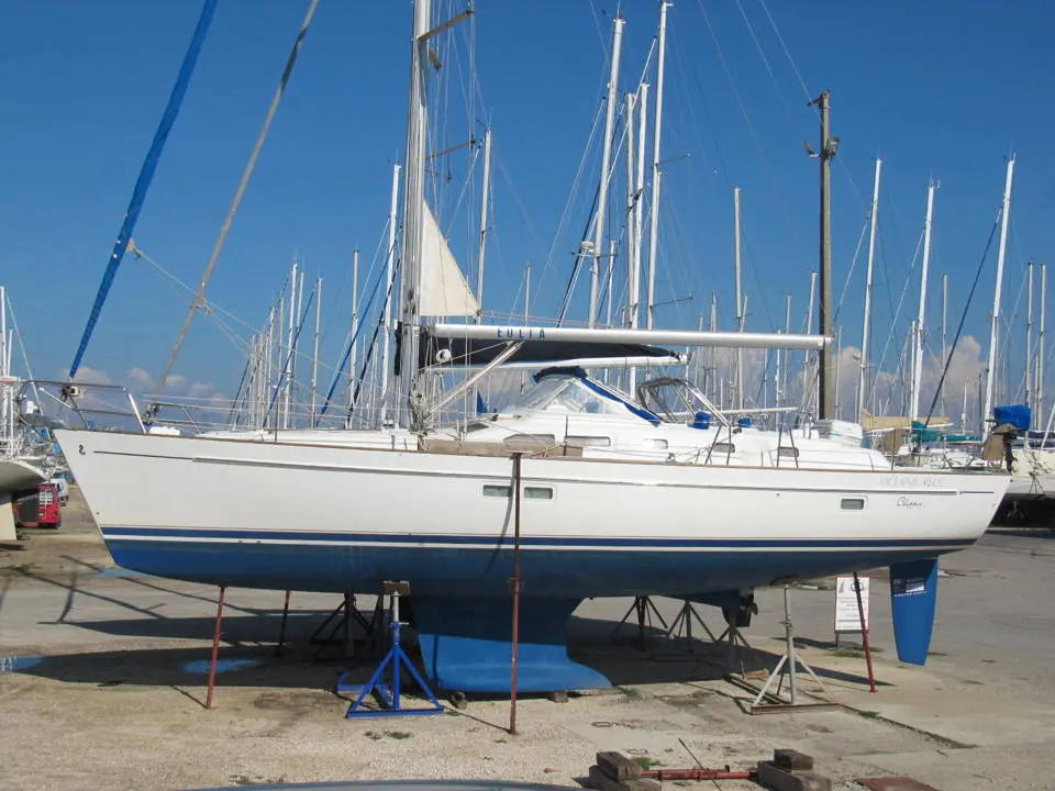 Beneteau Oceanis 42 CC — Voilier blanc à coque bleue présenté à terre dans une marina, vu de profil.