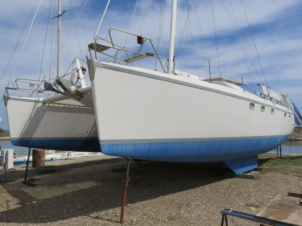 Jeantot Privilege 42 — Catamaran blanc et bleu posé à terre dans un chantier naval.