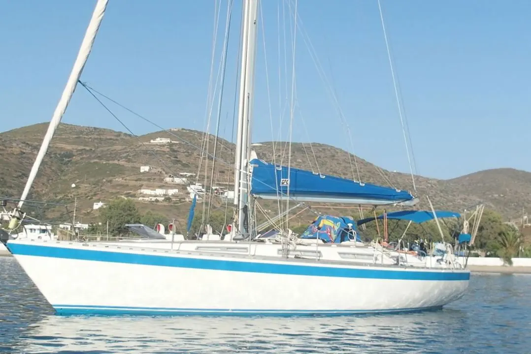 Wauquiez Centurion 42 — Voilier blanc et bleu vu de profil sur l’eau, avec une colline en arrière-plan.