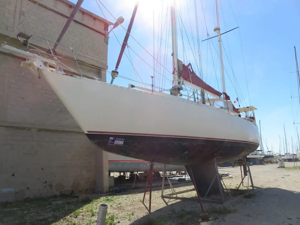 Metalu Jade 48 Ketch — Voilier blanc photographié à terre, vu de trois quarts avant dans un chantier naval.