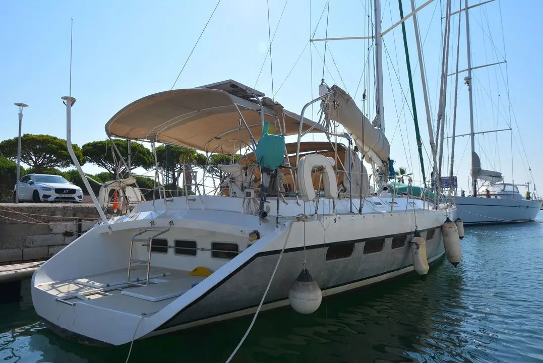 Alubat Cigale 16 — Voilier blanc amarré au port, vu de trois quarts arrière sous un ciel dégagé.