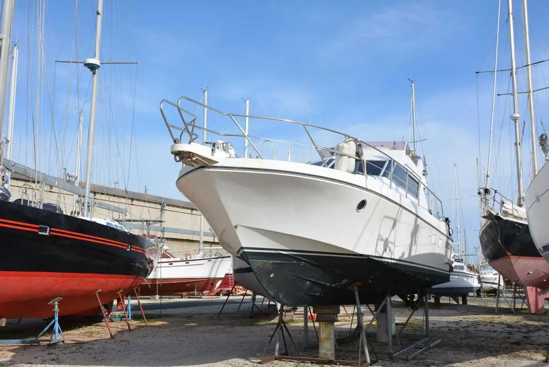 Guy Couach 1101 — Bateau à moteur blanc vu de trois quarts avant, posé sur bers dans un chantier naval.