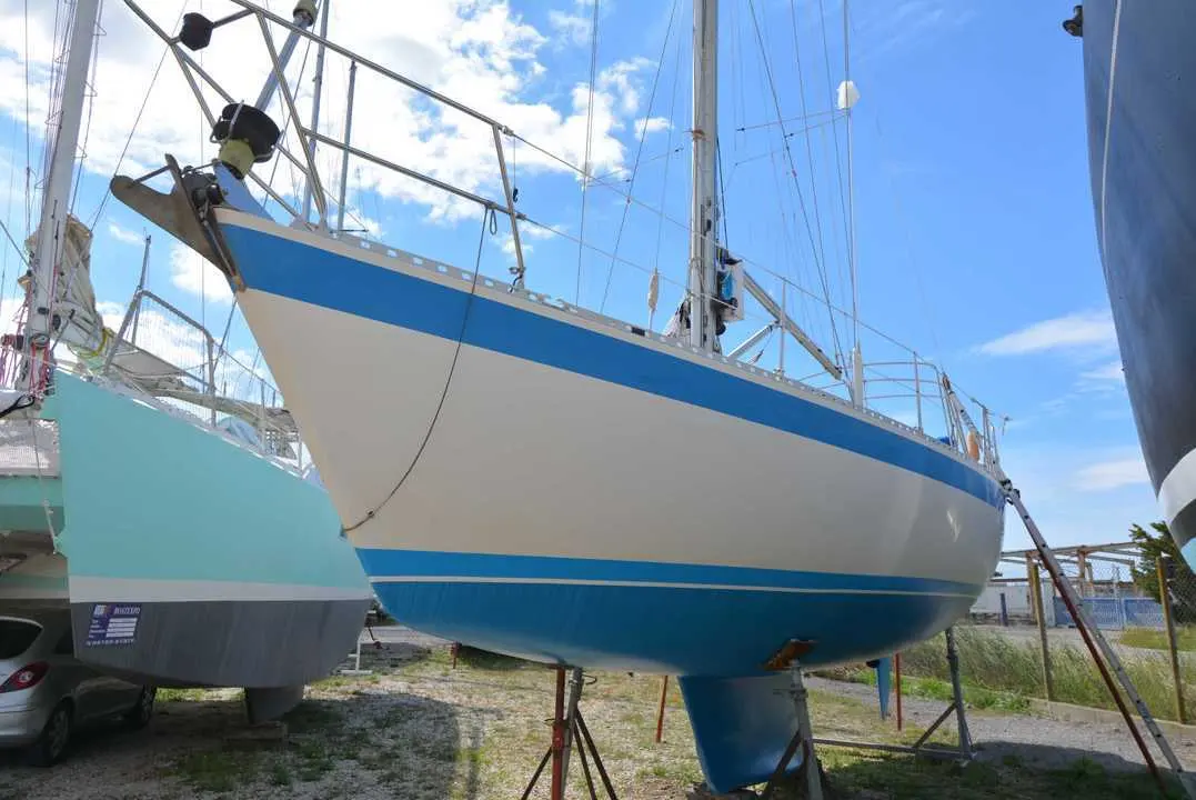 Wauquiez Centurion 36 — Voilier blanc et bleu posé à terre, photographié entre deux autres bateaux.