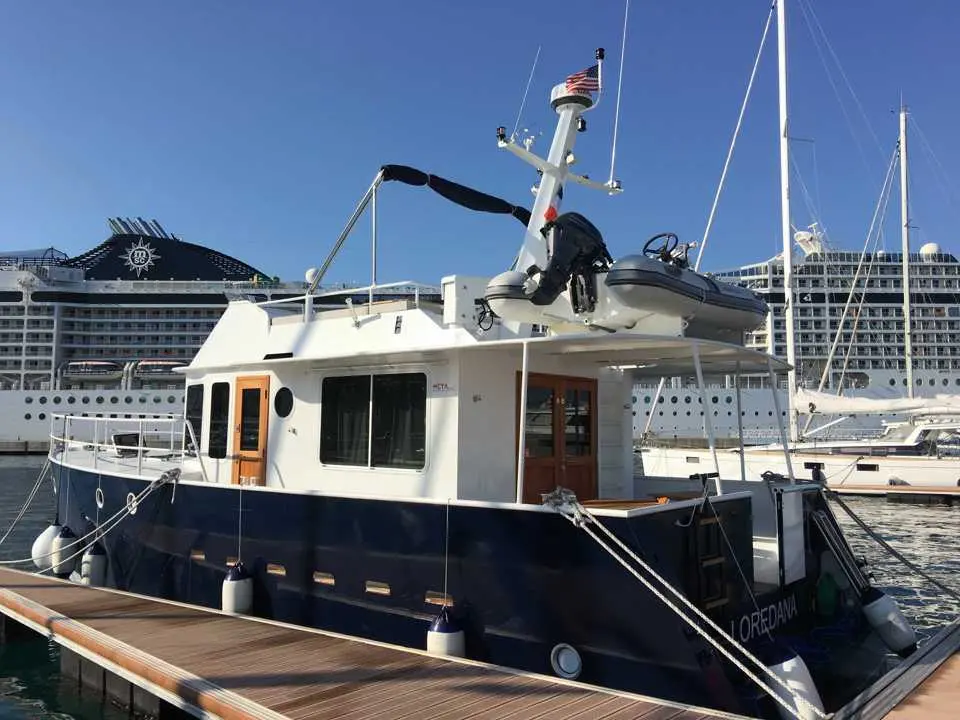Meta Sweet Trawler 45 — Bateau à moteur amarré, avec annexe sur le toit et paquebot en arrière-plan.