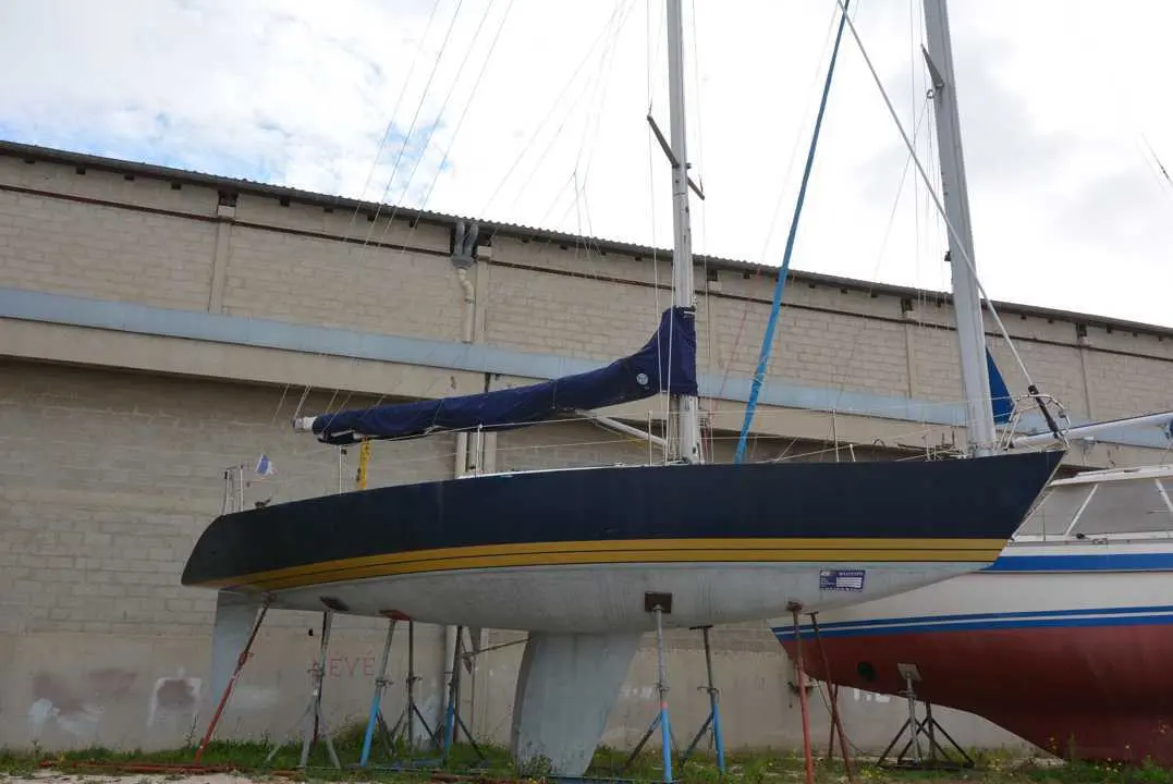 X-Yachts X-402 — Voilier bleu et blanc présenté à terre devant un bâtiment industriel.