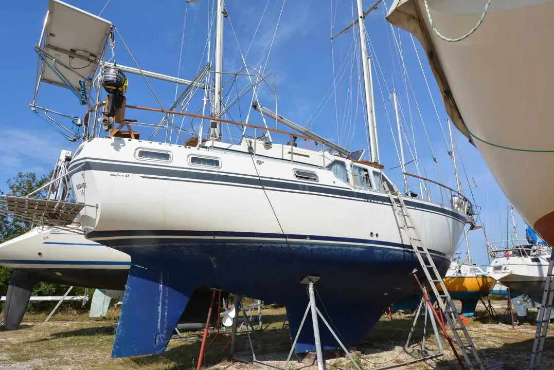 Siltala Yachts Nauticat 43 — Voilier blanc et bleu photographié à terre, entre deux autres bateaux.