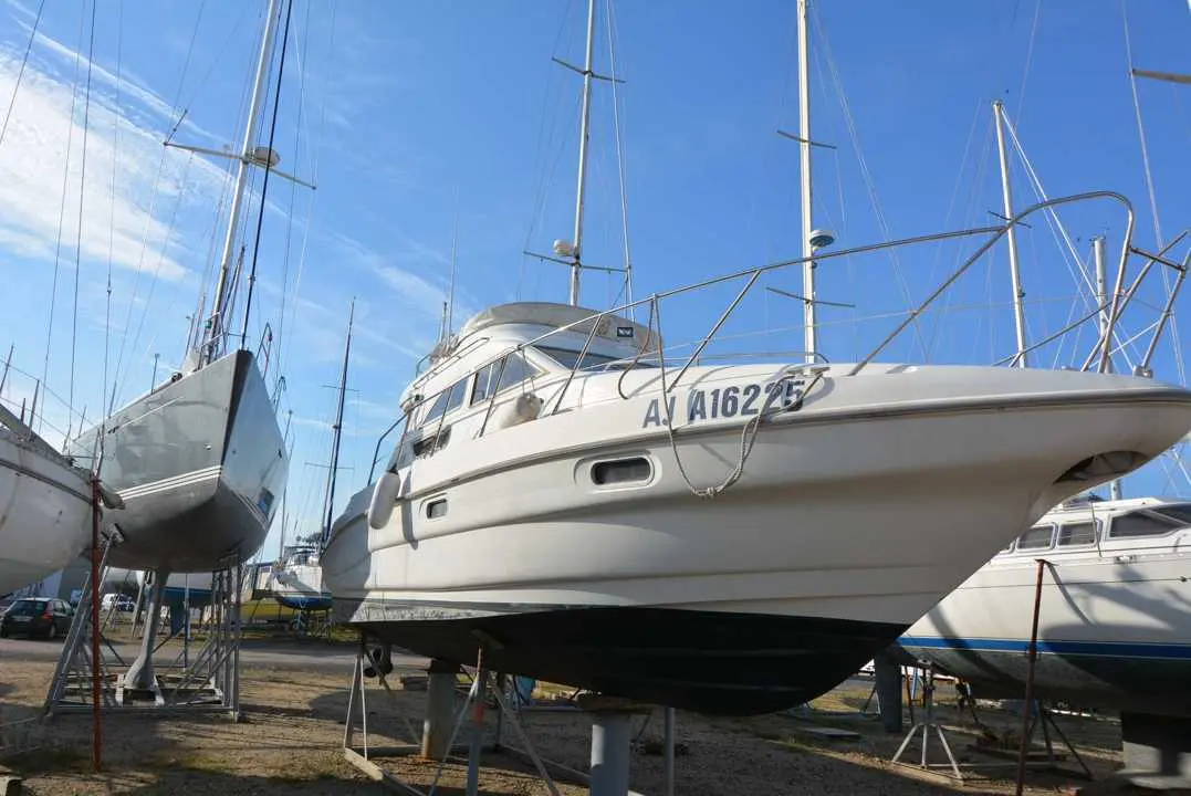 Sealine Statesman 330 — Vedette blanche à moteur vue de trois quarts sur bers dans un chantier naval.
