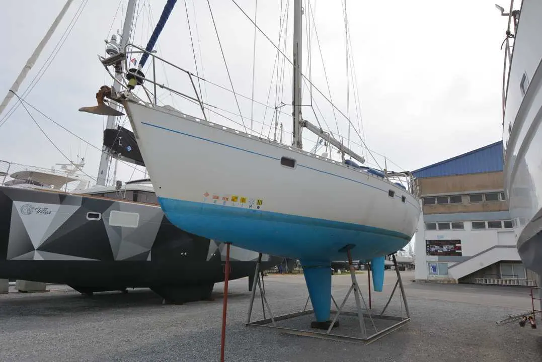 Kirie Feeling 446 — Voilier blanc et bleu présenté à terre sur bers dans un chantier naval.