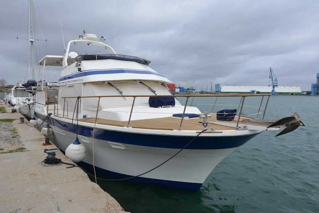 Tarquin Trader 41+2 — Bateau à moteur blanc et bleu amarré dans un port, vu de trois quarts avant.